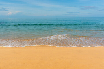 Fototapeta premium View of blue sky, blue sea, small wave and yellow sand that is signature of beautiful seascape scene at Phuket Province, Thailand in the morning of holiday.