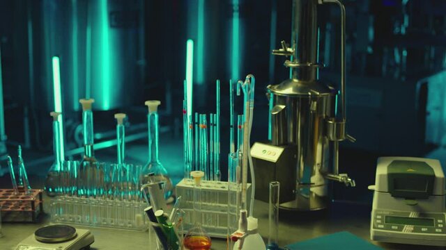 Medical or chemical development modern laboratory . Laboratory equipment , test tubes glasses on the table on background with blue lights . Dark room . Shot on ARRI ALEXA camera with dolly movement .
