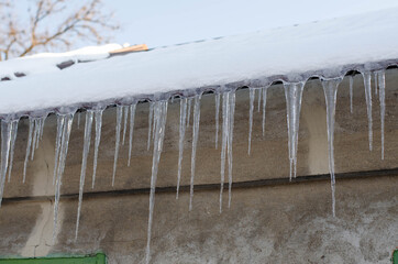Ice on the roof of the house. Icicles. Frozen water.