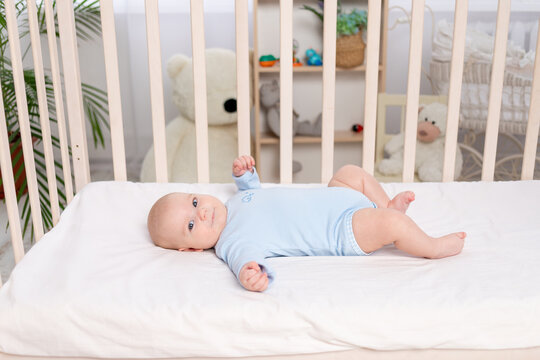 Baby In The Crib, Cute Little Boy Of Six Months Lying In The Nursery On The Bed