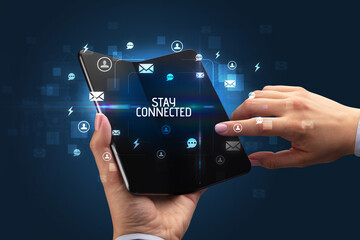 Businessman holding a foldable smartphone with STAY CONNECTED inscription, social networking concept