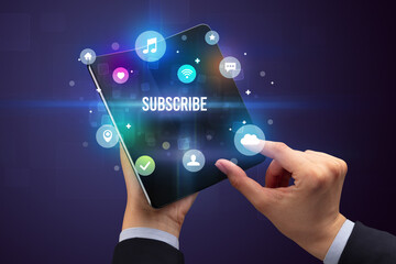 Businessman holding a foldable smartphone with SUBSCRIBE inscription, social media concept