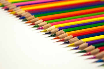 colored pencils lying in a row on white background