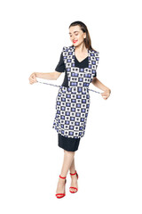 A young woman in a black dress and red shoes playfully knots an apron of a housewife isolated on a white background