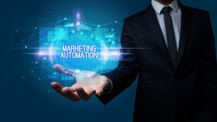 Man hand holding MARKETING AUTOMATION inscription, technology concept