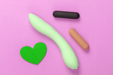 Sex concept. Sex toys and red heart on pink background. Top view
