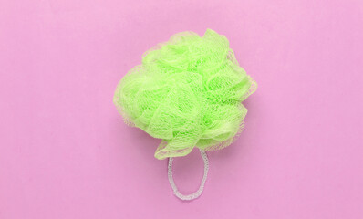Green bath sponge on a pink pastel background. Top view. Minimalism