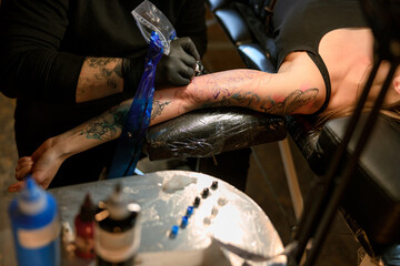 Obraz premium Professional male bearded caucasian tattoo master is working in cozy atmospheric studio
