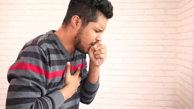 young asian man coughing and sneezes close up 
