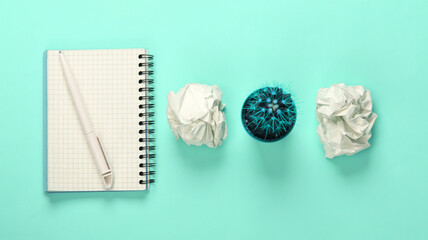 Obraz na płótnie Canvas Crumpled paper balls, cactus pot and notepad on blue pastel background. Working space