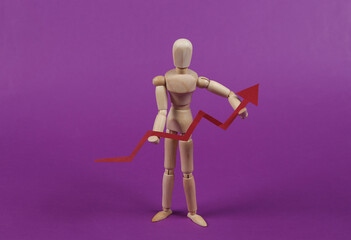 Wooden puppet mannequin holding a growth arrow on a purple background. Economic rise, business concept