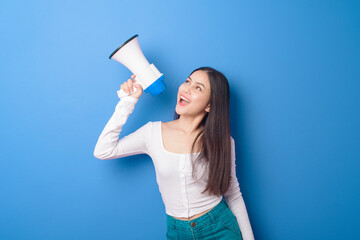portrait of young beautiful smiling woman is using megaphone to announce over isolated blue...