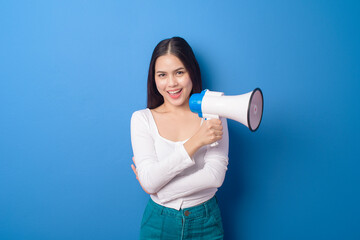 portrait of young beautiful smiling woman is using megaphone to announce over isolated blue...