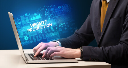 Businessman working on laptop with WEBSITE PRODUCTION inscription, cyber technology concept