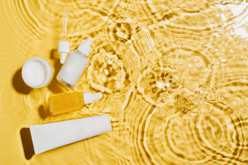 Bottle serum and tube cream balance cosmetic in clean transparent water with sunlight on yellow background