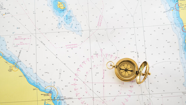 Retro styled golden compass (sundial) and old white nautical chart close-up. Vintage still life. Sailing accessories. Travel, navigation, history, collecting, hobby. Panoramic image, copy space