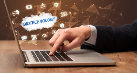 Businessman working on laptop with BIOTECHNOLOGY inscription, modern technology concept