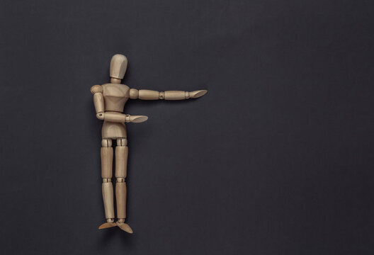 Wooden puppet mannequin shows empty space for your text on gray background. Copy space