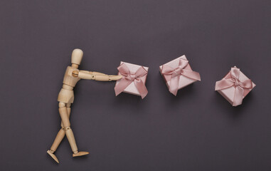 Wooden puppet mannequin and gift boxes on gray background