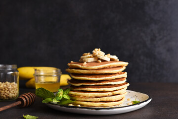 Homemade pancakes with banana and pine nuts on a dark background