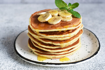 Homemade pancakes with banana, honey and mint on the kitchen table.