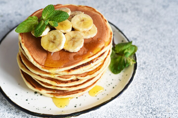 Homemade pancakes with banana, honey and mint on the kitchen table.