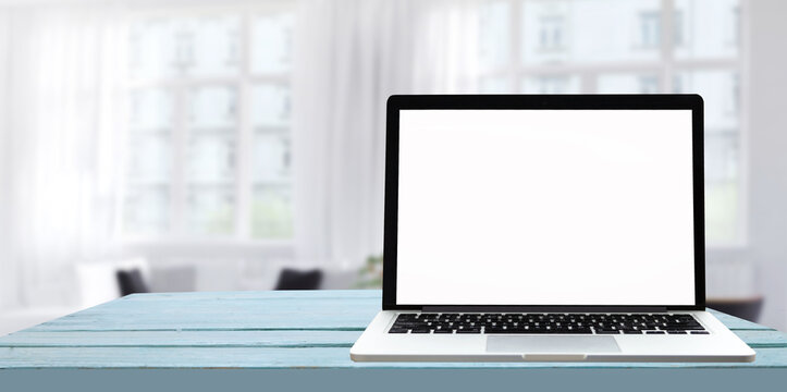Laptop with blank screen on white table with office window view. Home interior or office background