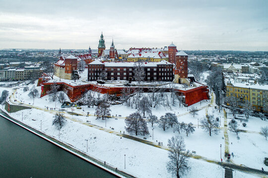 Historic royal Wawel Castle and Cathedral in Karkow, Poland, with Vistula River, walking people, snow and promenade in winter