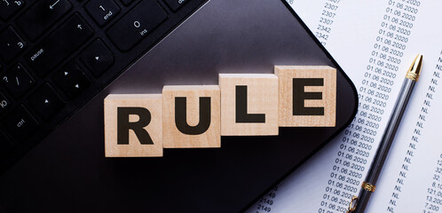 The word RULE is written on wooden cubes on the keyboard next to the pen.