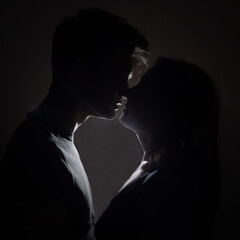 Side view of happy young couple celebrating Valentine's Day together. Beautiful couple is kissing. Beautiful young couple smiling while sitting face to face