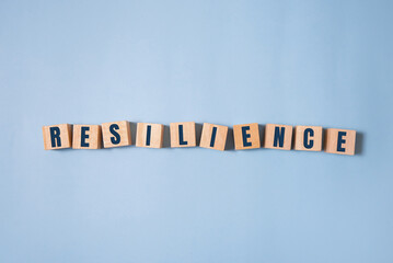 Resilience word concept on cubes on blue background.