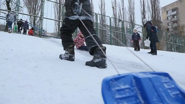 A guy pulls a sleigh on a snowy hill. Slow motion 01.10.2020 Ukraine, Kiev. HD