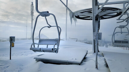 A frozen and abandoned Chairlift in the snowy mountains. A devastated ska lift covered with snow and frost.