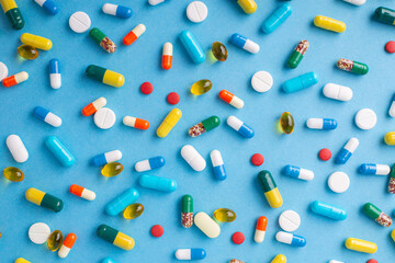 Pills of different shape and colour on a light blue background. Concept of medicine, treatment