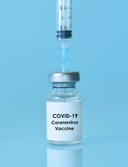 Vaccine in a bottle with a syringe on a blue background.The concept of medicine, healthcare and science.Coronavirus vaccine.Copy space for text.