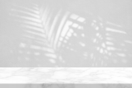 White Marble Table with Palm Leaves Shadow on Wall Texture Background, Suitable for Product Presentation Backdrop, Display, and Mock up.