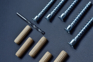 furniture assembly fittings and drill. lie on a dark background. close-up.