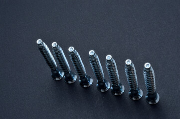 furniture screws euro screws. lie on a dark background. close-up.