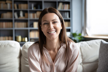 Head shot portrait smiling woman making video call to friends or relatives, using webcam, sitting...