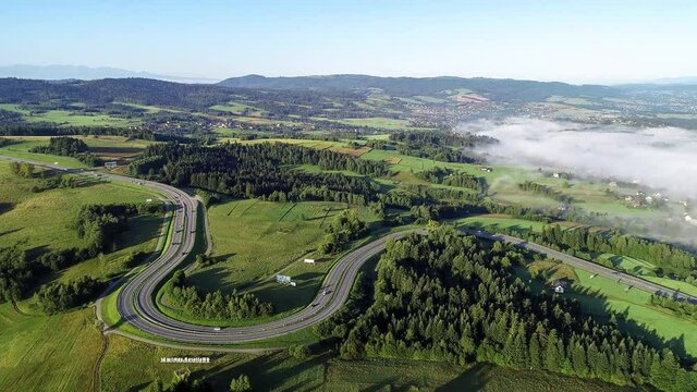 Poland. Winding switchback road from Krakow to Zakopane, called Zakopianka, near Rabka and Chabowka. Aerial video in sunrise light with morning fog. Far view of Tatra mountains in the background