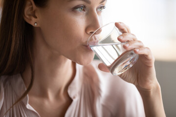 Close up attractive woman drinking pure fresh mineral water, preventing dehydration, young female...