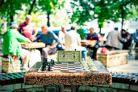 Chess board with pieces and clock on wooden desk In connection with the chess tournament. Chess pieces and stopwatch on a board in the park. toned