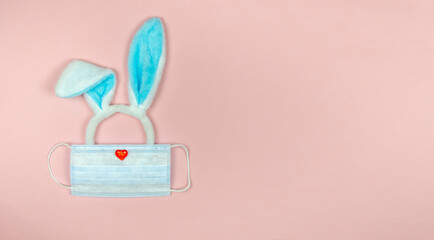 Rabbit ears on a pink background in a medical mask.Easter 2021