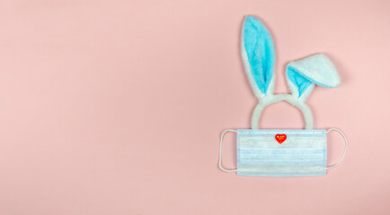 Rabbit ears on a pink background in a medical mask.Easter 2021