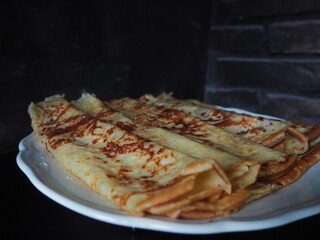 Homemade crepes, french crêpes, traditionally made for Candlemas, on black and brick wall background