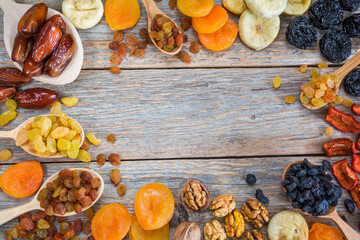 Frame of different dried fruits on a wooden background