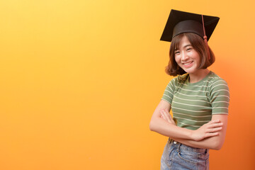 Portrait of young Asian student wearing graduation cap over studio background.