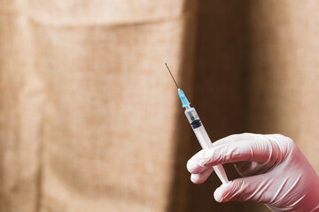 hand with gloves holding the syringe . Covid-19 or coronavirus vaccine