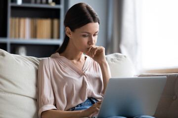 Close up thoughtful upset woman looking at laptop screen, pondering ideas or difficult tasks,...