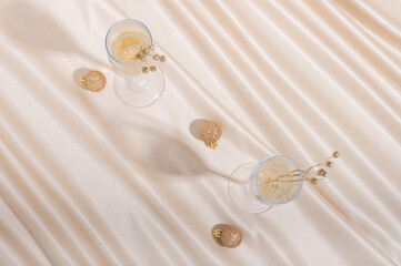 Creative concept made of champaign glasses with flax seeds and Christmas baubles on pastel silk sheet